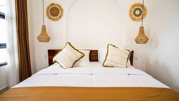 A neatly made bed with two pillows, a brown bedspread, and two wall-mounted lamps.