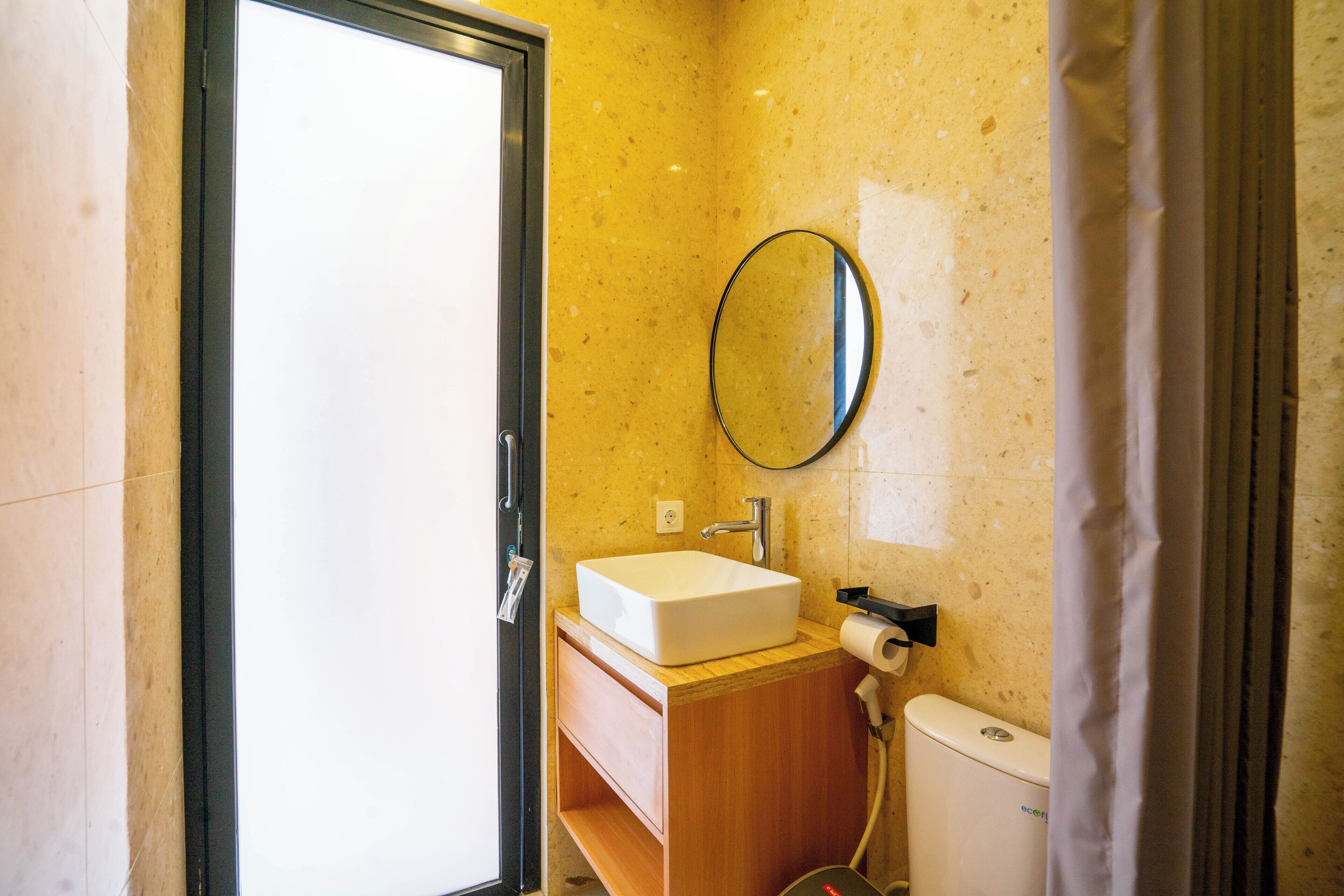 Et badeværelse med en hvid vask, et spejl og et toilet.