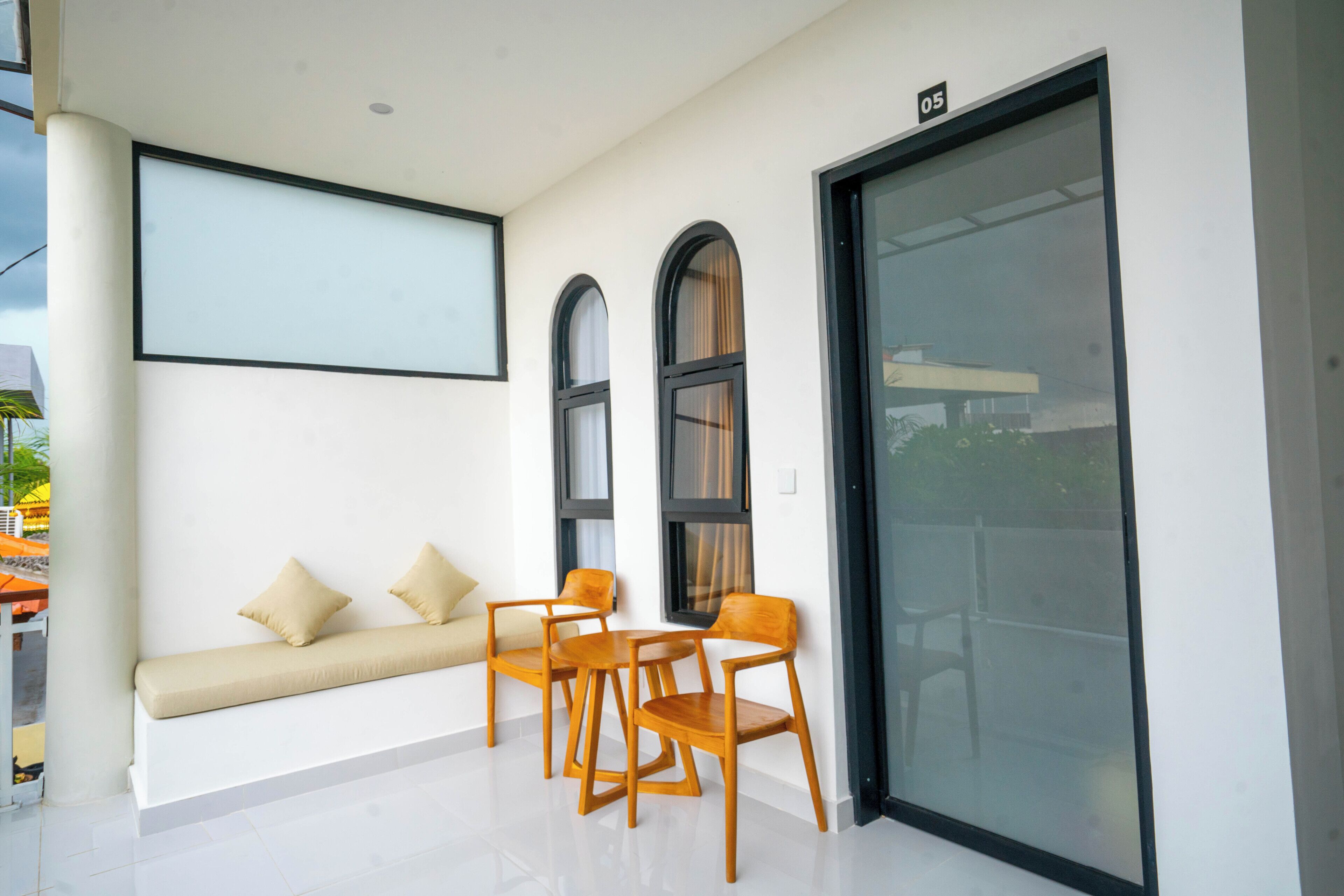 A modern interior with a white wall, a sofa with cushions, and a table with chairs.