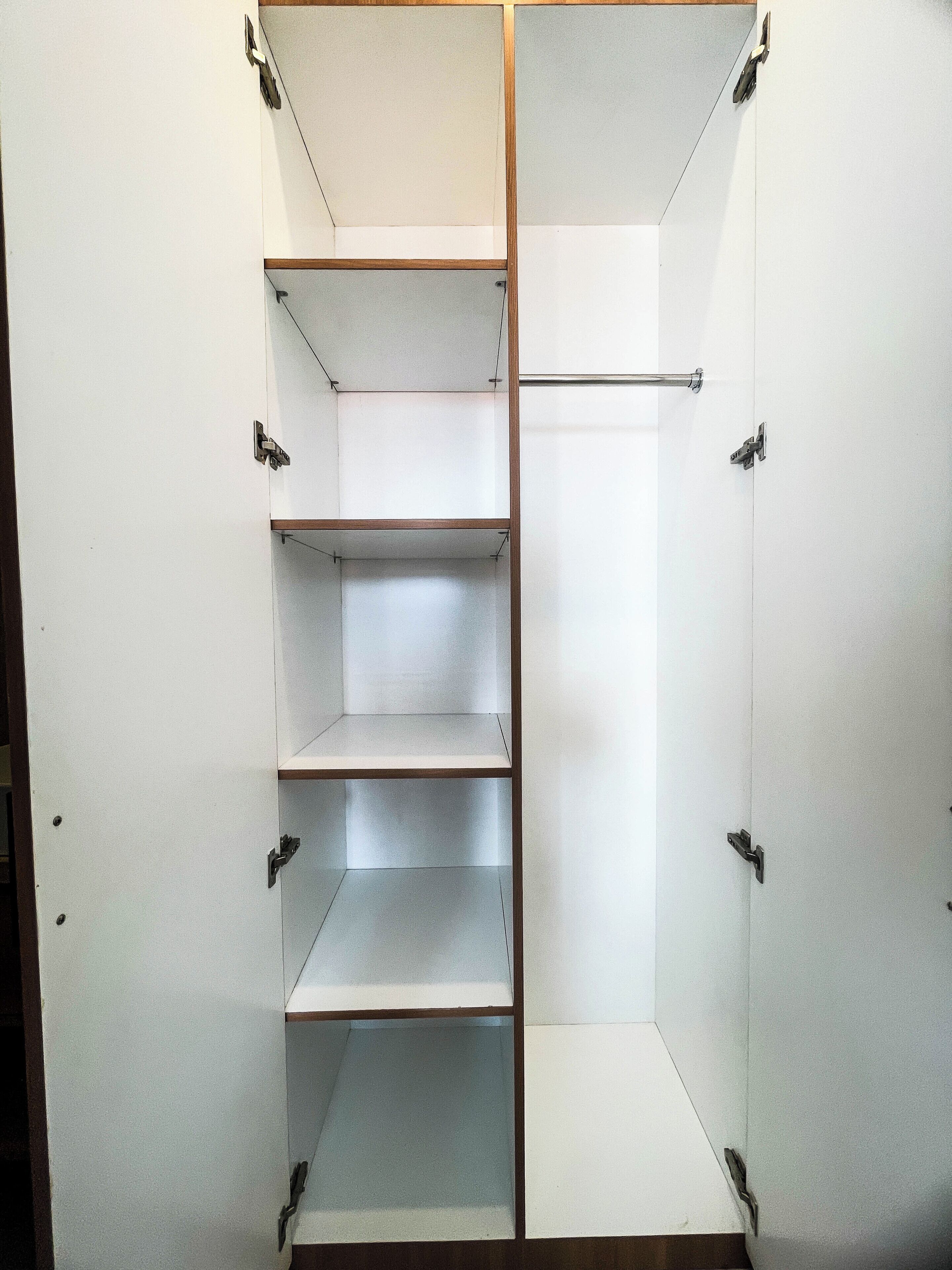 Armadio a muro con scaffali multipli e un'asta centrale per appendere i vestiti.