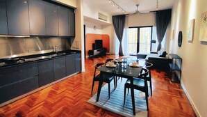 Une cuisine moderne avec des meubles de couleur sombre et un coin repas doté d’un plancher en bois.