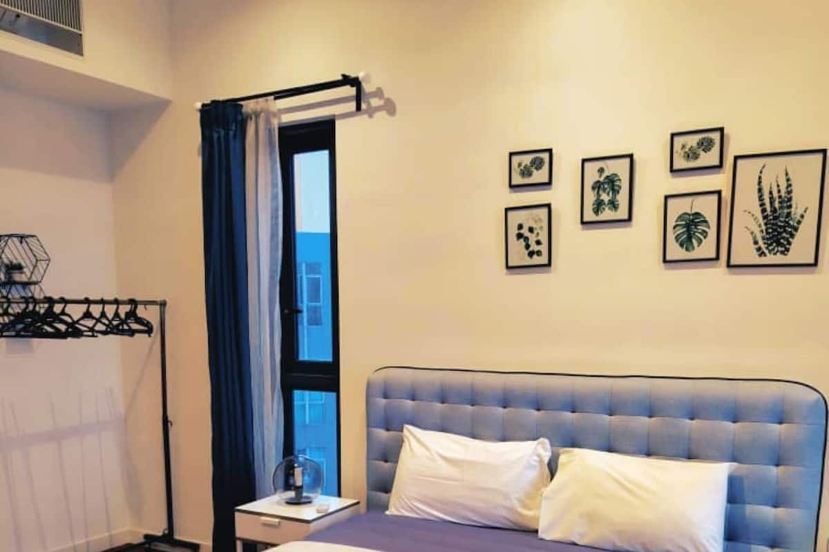 A neatly made bed with white linens and towels, a tufted headboard, and a bedside table with a lamp.