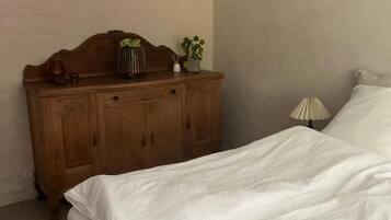 A bedroom with a bed, a wooden dresser, and a lamp.