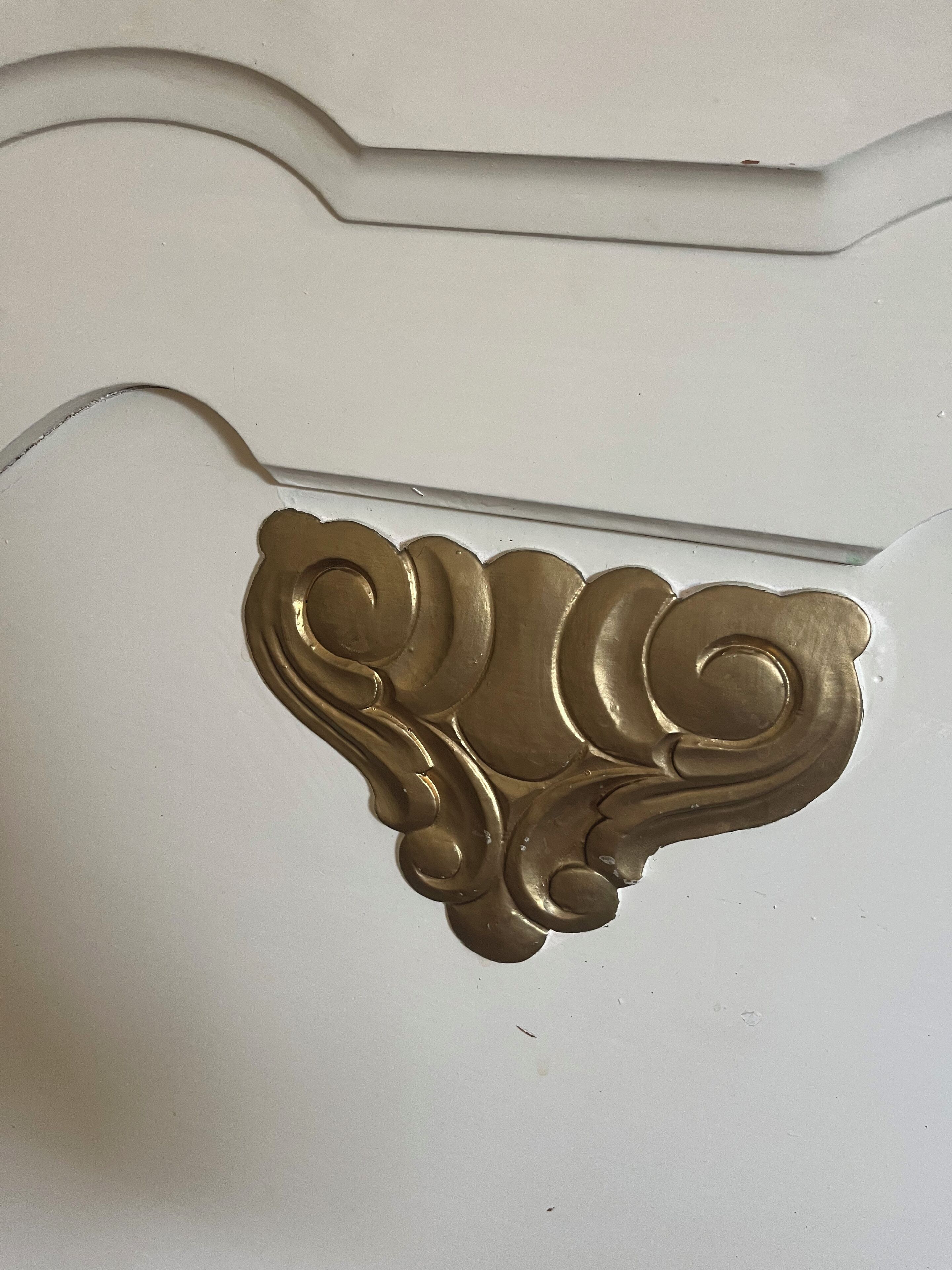 Una pared blanca con un elegante moldurón dorado.