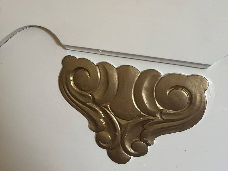 Una pared blanca con un elegante moldurón dorado.