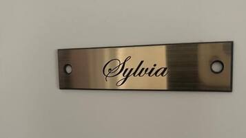 A metallic nameplate with the name "Sylvia" mounted on a wall.