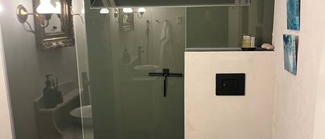 A modern bathroom with a glass shower enclosure, a white sink with a marble countertop, and a black toilet.