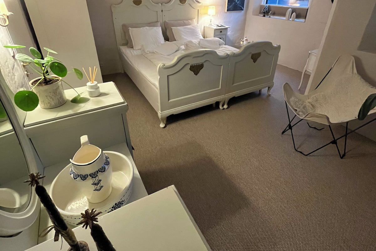 A bedroom with a bed, bedside tables, a chair, a dresser, and a window.
