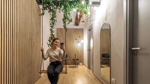 A modern interior with a wooden slat wall, a hanging plant, a mirror, and a small table with a chair. - Wine Apartments Florence Biancone (Florence)