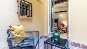 A balcony with a black metal chair and a table, a yellow cushion, and a vase with flowers. - Wine Apartments Florence Biancone (Florence)