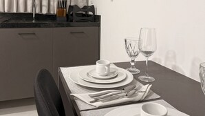 Une cuisine moderne avec un coin repas aménagé pour deux personnes. Elle comprend un plan de travail, une table à manger avec des assiettes, des verres et des couverts.