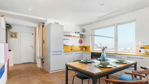 Eine moderne Küche mit Essbereich, Holzboden und einem großen Fenster mit Blick auf die Stadt.