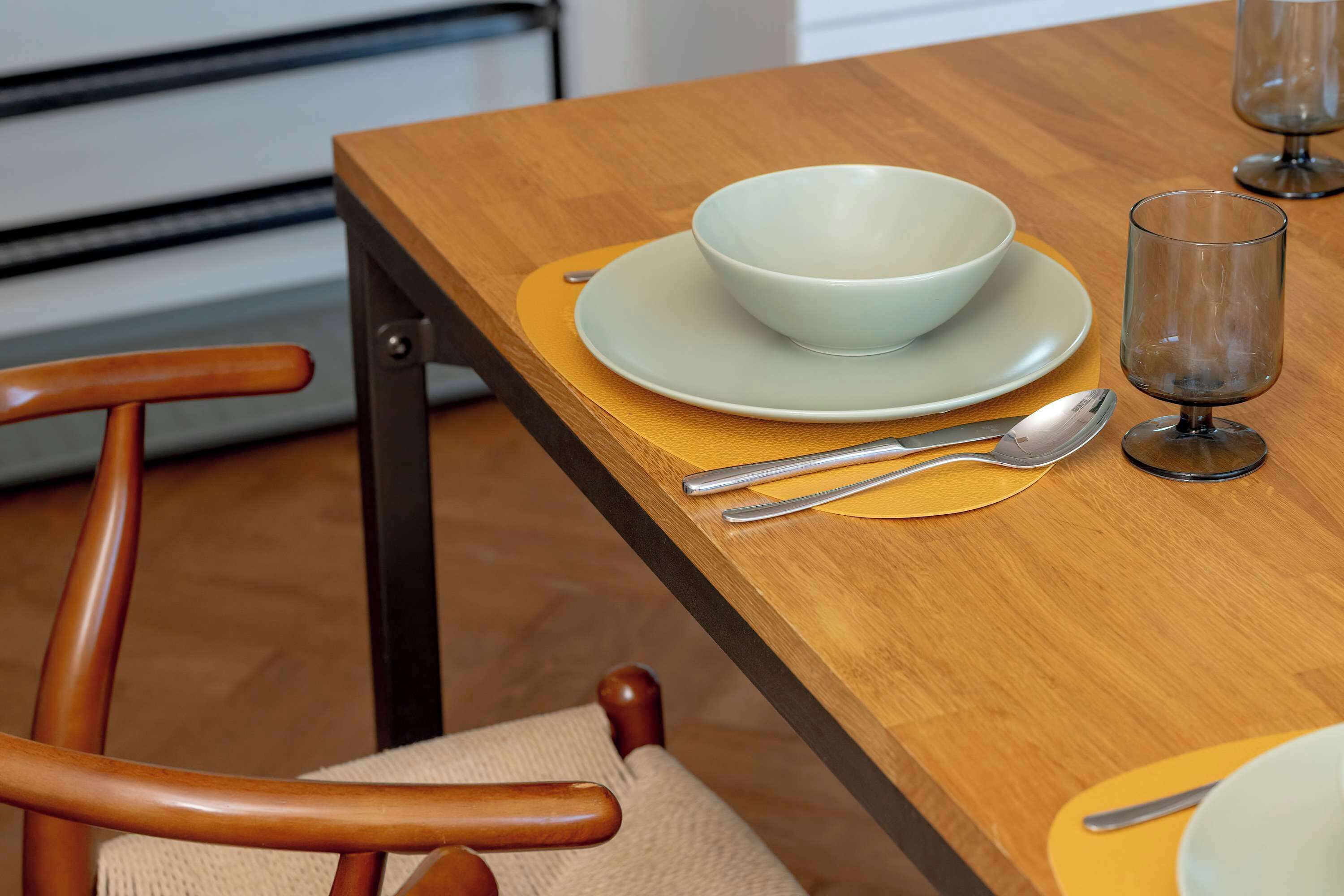 Una mesa de madera con un bol, un plato y un vaso sobre una servilleta amarilla.