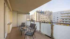 Un balcone con tavolo e sedie, vista sugli edifici circostanti e un recinto bianco.