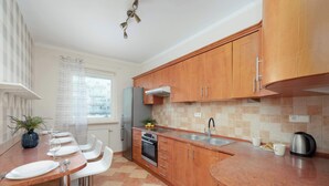 Una cucina moderna con mobili in legno, un frigorifero in acciaio inossidabile, un forno integrato e un'ampia finestra con vista sulla città.