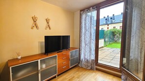 Een kamer met een houten kast, een televisie en een schuifdeur naar een tuin.