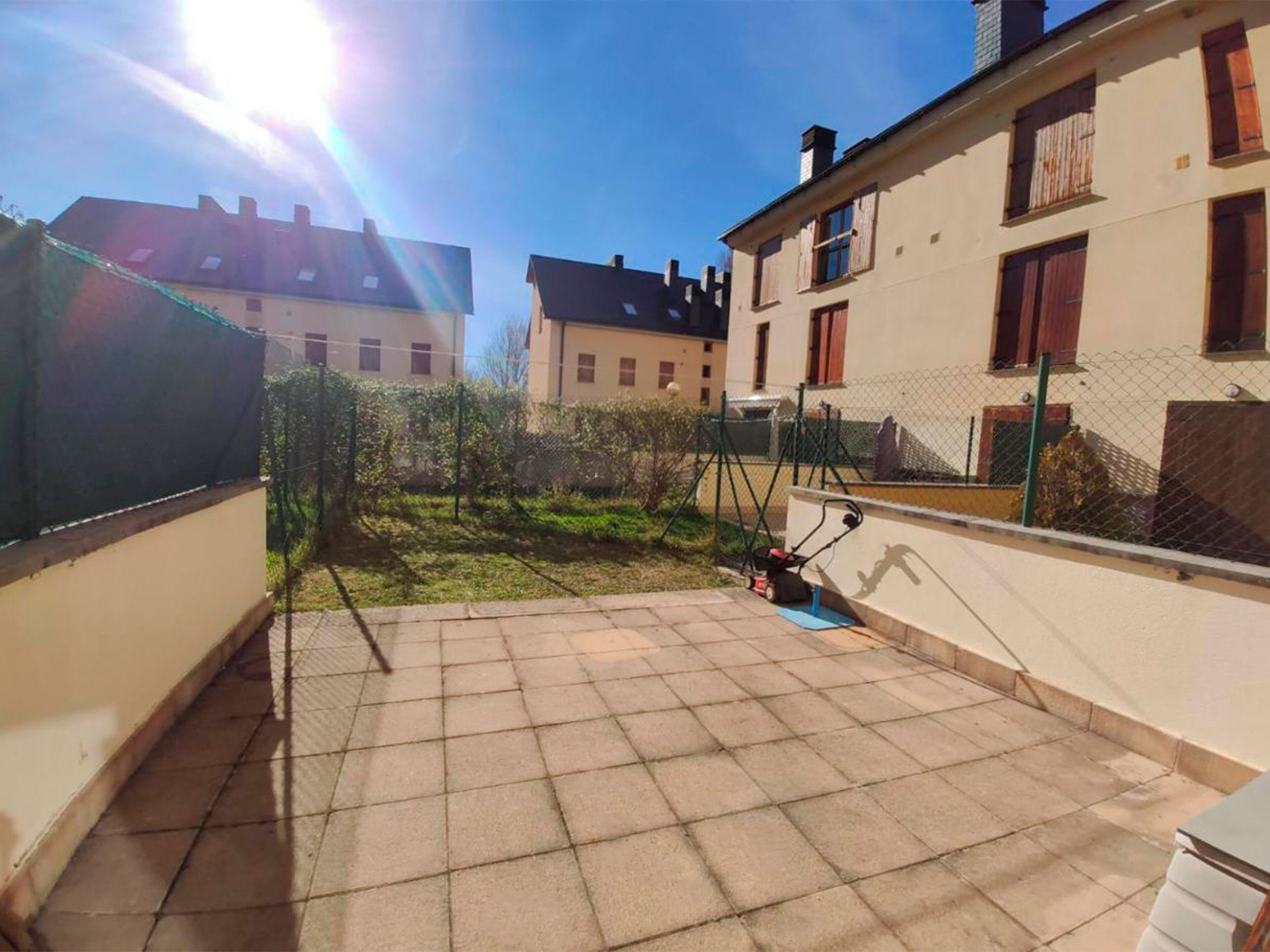 Une terrasse sur le toit avec une pelouse, une tondeuse à gazon et une clôture.
