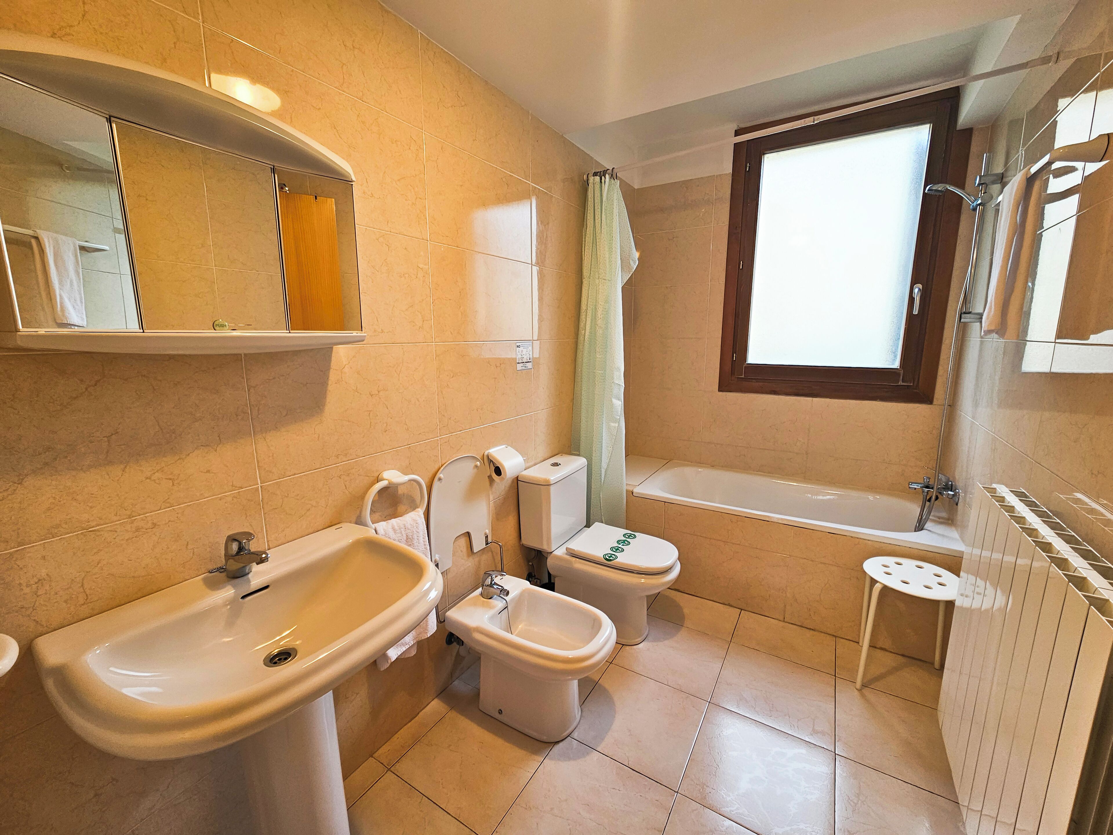 A bathroom with a sink, toilet, bidet, and bathtub.