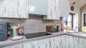Eine Küche mit modernem Design, inklusive einer eingebauten Mikrowelle, einer Kaffeemaschine und einer Obstschale auf der Arbeitsfläche.