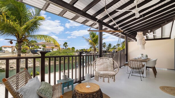 A covered outdoor area with wicker furniture, a table, and a hanging light fixture. - Waterlands Village Bonaire, Kas Palma with private pool! (Kralendijk)