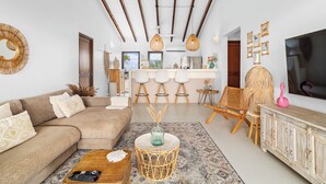 A modern living room with a sofa, a coffee table, and a dining area with bar stools. - Waterlands Village Bonaire, Kas Palma with private pool! (Kralendijk)