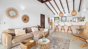 A modern living room with a sofa, coffee table, and a dining area with bar stools. - Waterlands Village Bonaire, Kas Palma with private pool! (Kralendijk)