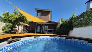Uma piscina com azulejos azuis, um deck de madeira e uma casa ao fundo.