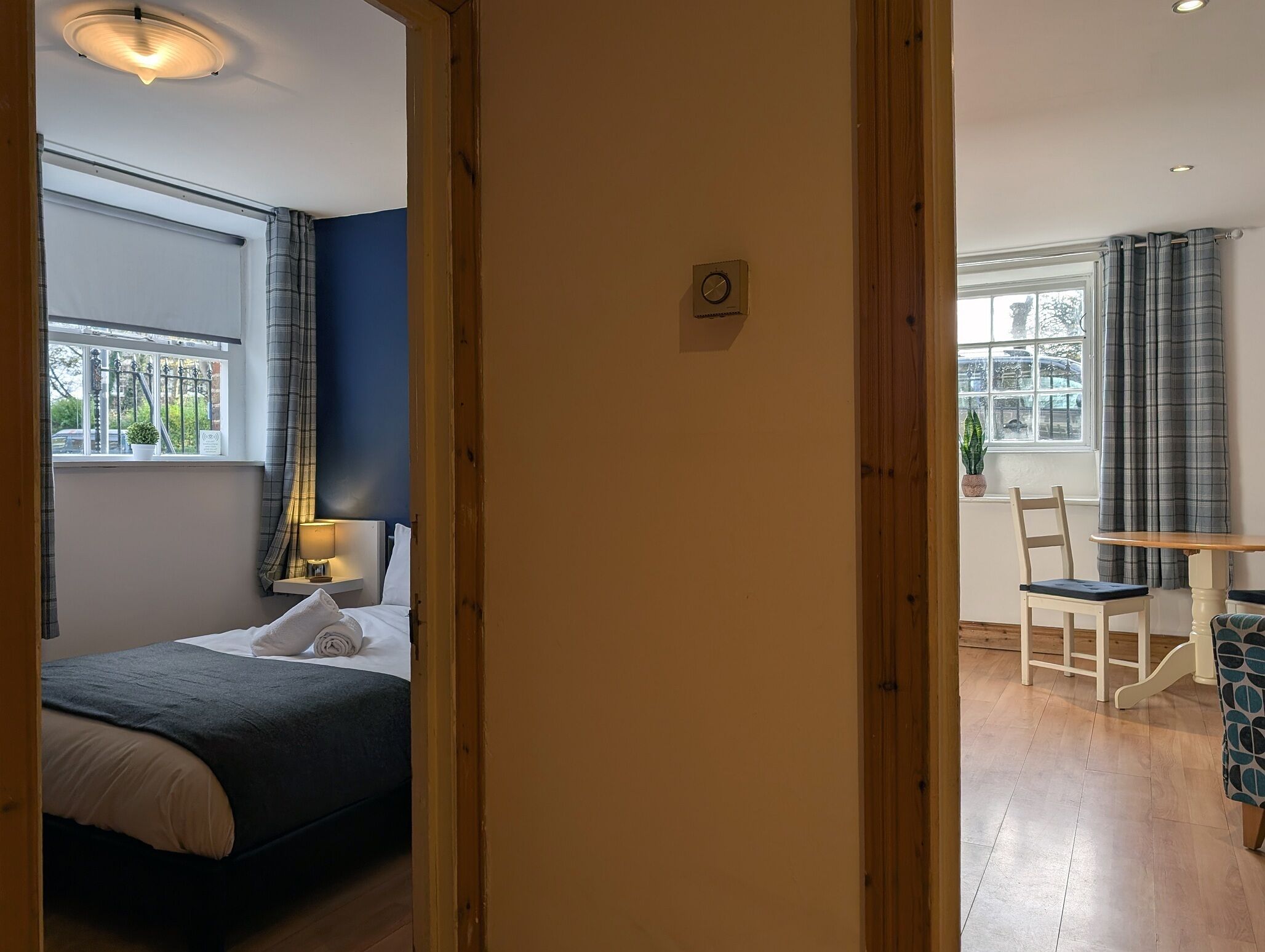 Un dormitorio con cama, mesita de noche, lámpara y ventana con cortinas.