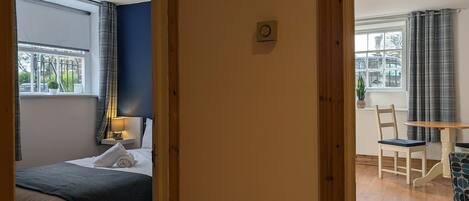 Un dormitorio con cama, mesita de noche, lámpara y ventana con cortinas.