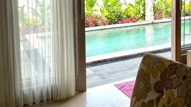 A room with a view of a swimming pool, a patterned sofa, and a decorative wooden lattice. - Bale Jiwanmukti Narmada (Narmada)