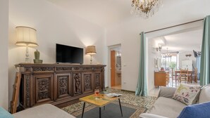 Ein Wohnzimmer mit Fernseher, zwei Lampen, einer Couch, einem Couchtisch und einem gemusterten Teppich.