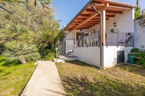 A house with a covered patio, a concrete pathway, and a small garden area.