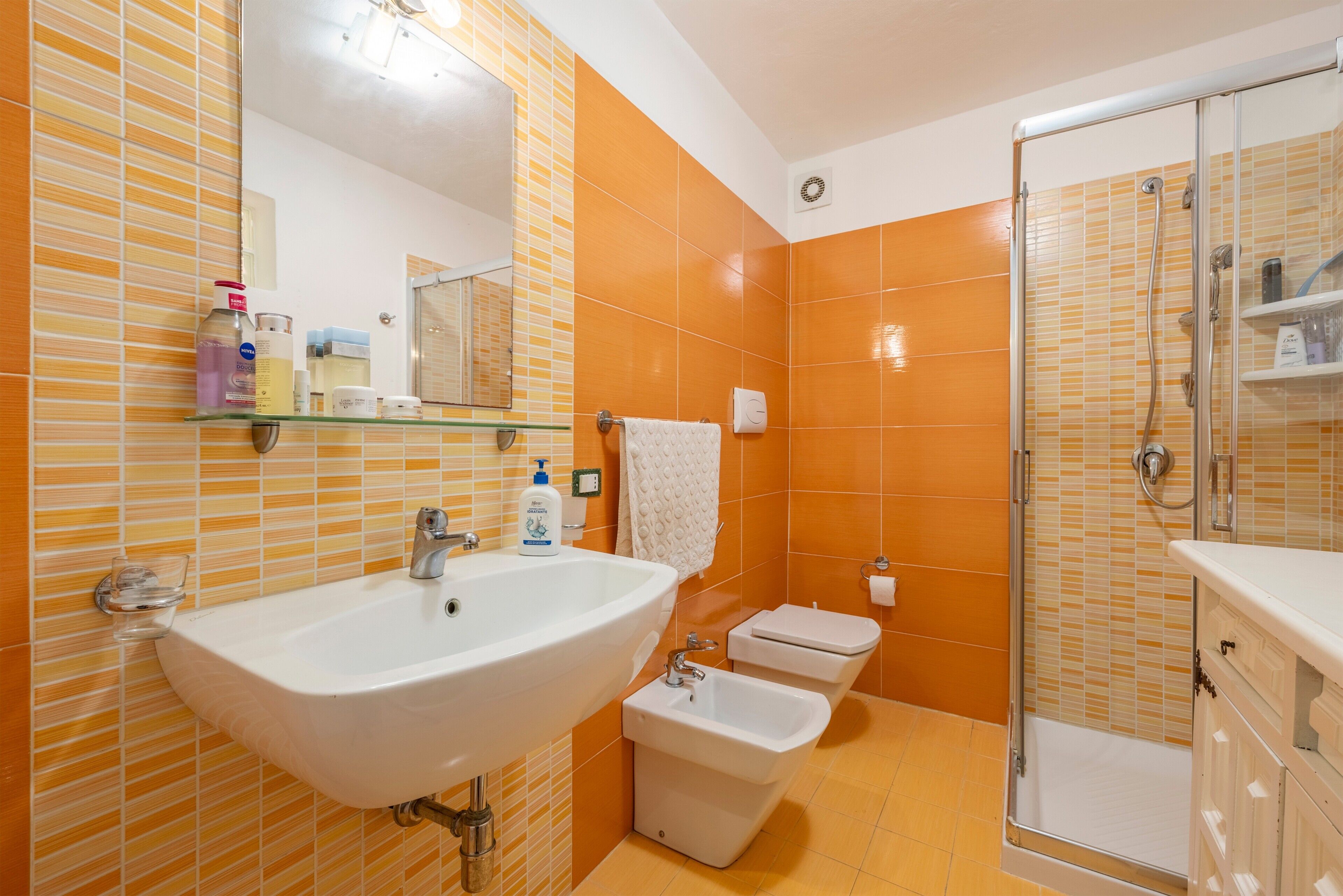 A bathroom with a sink, bidet, and glass-enclosed shower.