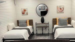A modern bedroom with two beds, a round mirror, and artwork on the walls. - 3-bedroom townhome in fabulous Longboat Key with stunning views and boat dock (Longboat Key)