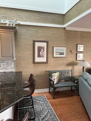 A modern living room with a wooden accent wall, a dining area with a marble countertop, and a seating area with a patterned rug. - 3-bedroom townhome in fabulous Longboat Key with stunning views and boat dock (Longboat Key)