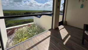 A balcony with a view of a water body and greenery, wooden flooring, and a chair. - 3-bedroom townhome in fabulous Longboat Key with stunning views and boat dock (Longboat Key)