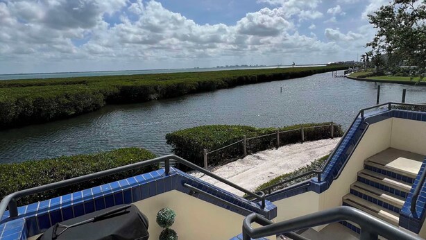 A balcony with a view of a water body and a distant shoreline. - 3-bedroom townhome in fabulous Longboat Key with stunning views and boat dock (Longboat Key)