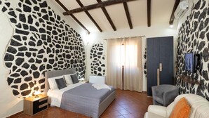 Ein Schlafzimmer mit einer Wand im Steinmuster, einem Bett, einem Fernseher und einer Sitzecke.