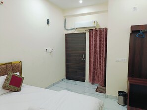 A hotel room with a bed, a wardrobe, a door, and an air conditioning unit. - Mahalaxmi Guest House (Varanasi)