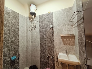 A bathroom with a shower, a sink, and a towel rack. - Mahalaxmi Guest House (Varanasi)