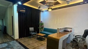 Un espacio de oficina moderno con suelo de madera, un sofá azul, un escritorio y un ventilador de techo.