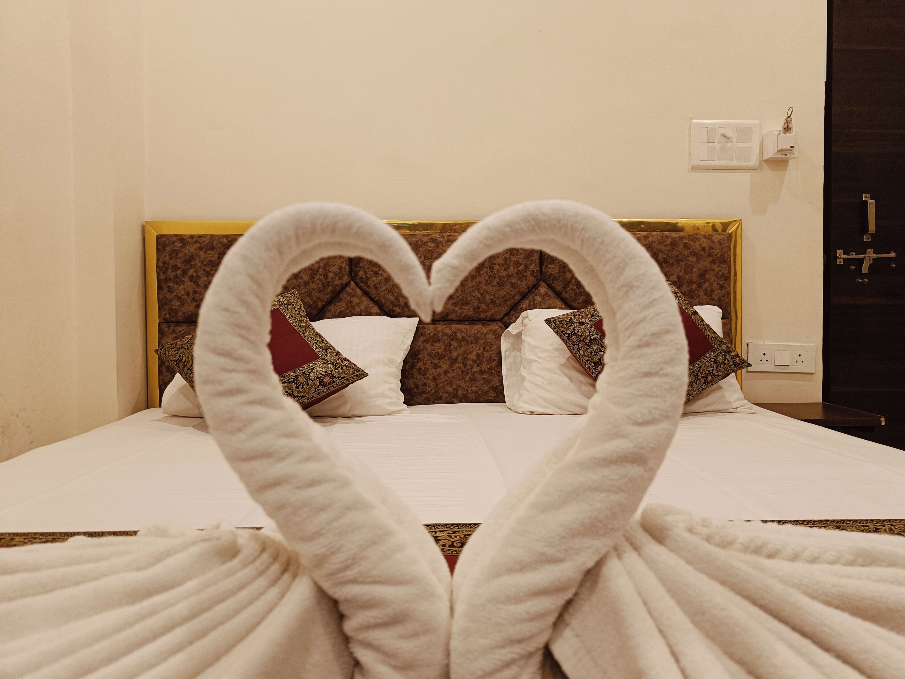 Ein Hotelzimmer mit einem Bett, das mit einer herzförmigen Handtuchgestaltung dekoriert ist.