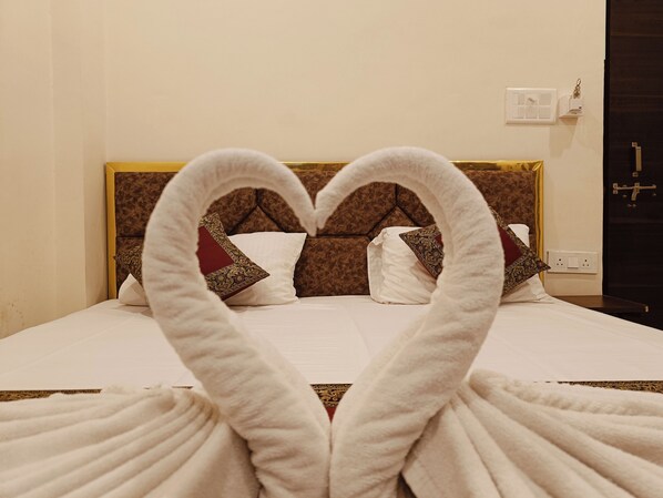 Habitación de hotel con una cama y una toalla dispuesta en forma de corazón.