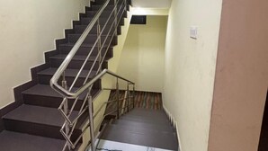 Una escalera con barandilla de metal, paredes color crema y suelo de mármol.