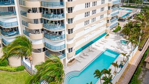 Ein mehrstöckiges Hotel mit Balkonen, einem Swimmingpool und Palmen.