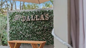 Een houten bank voor een muur met een Dallas bord en klimop.