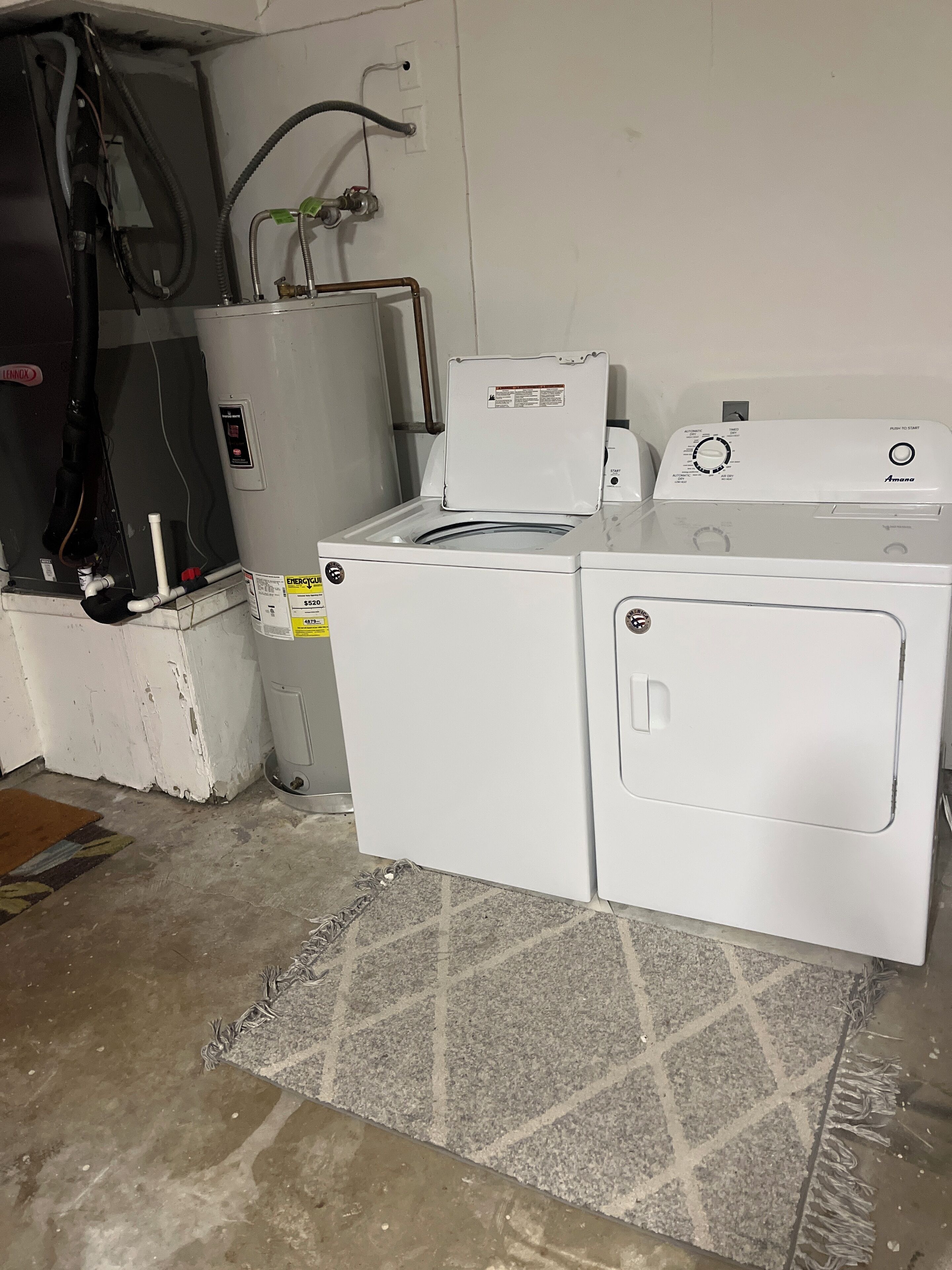 A laundry room with two white washing machines, a dryer, and a water heater.
