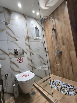 Ein Badezimmer mit Toilette, Dusche und einem Rauchverbot-Schild.