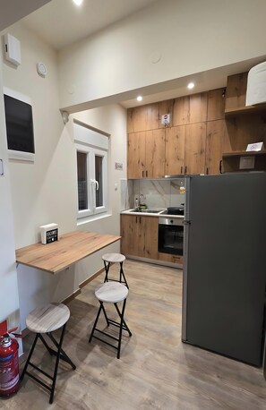 Eine kompakte Küche mit Holzausstattung, einem Backofen, einem Kühlschrank und einem kleinen Fenster.