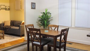 A dining area with a wooden table and four chairs, a potted plant, and a sofa in the background. - Downtown Detroit Getaway (Detroit)